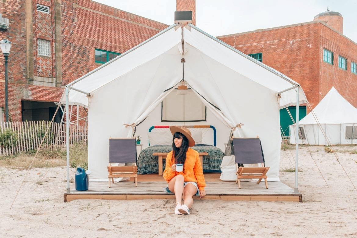 Women sitting in front of platform glamping tent on Rockaway Beach, New York.