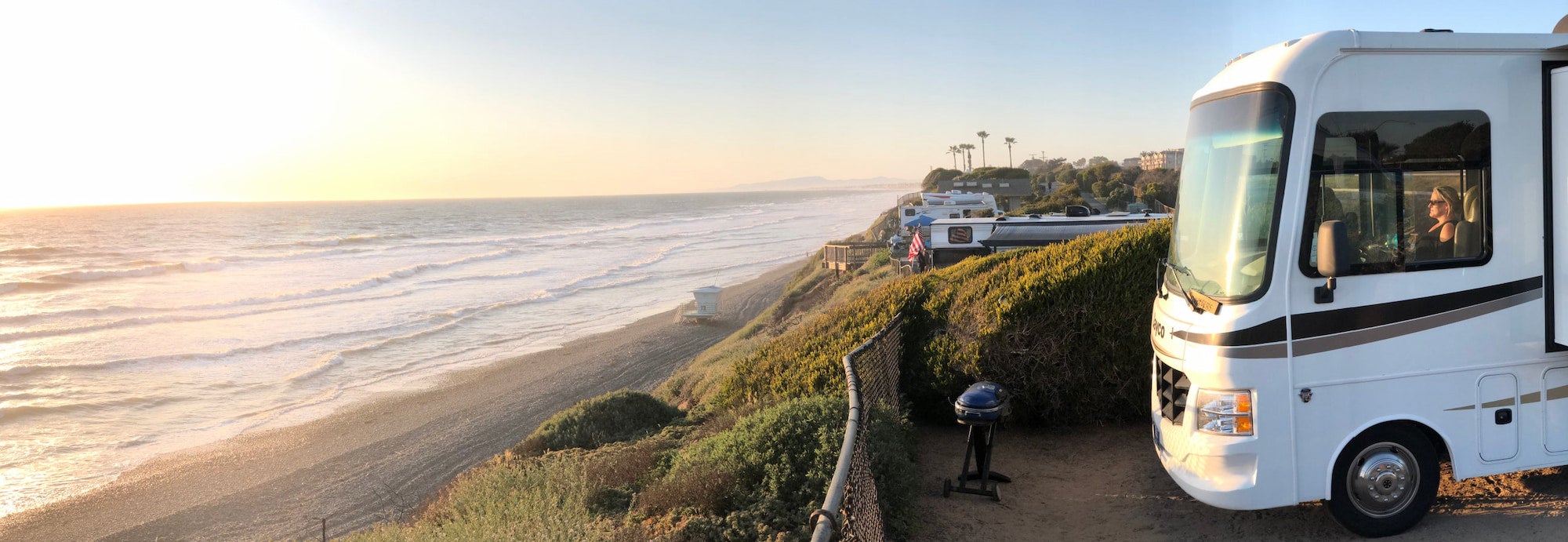 RV parked on edge of cliff overlooking the beach.