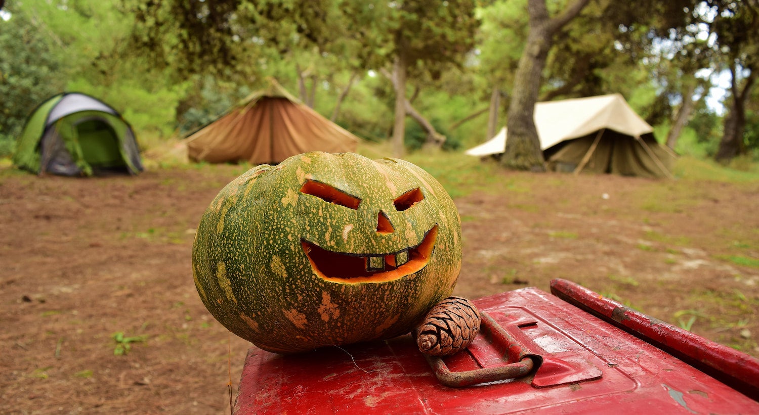 Jack o' lantern carved in front of tent at a campsite for halloween camping.