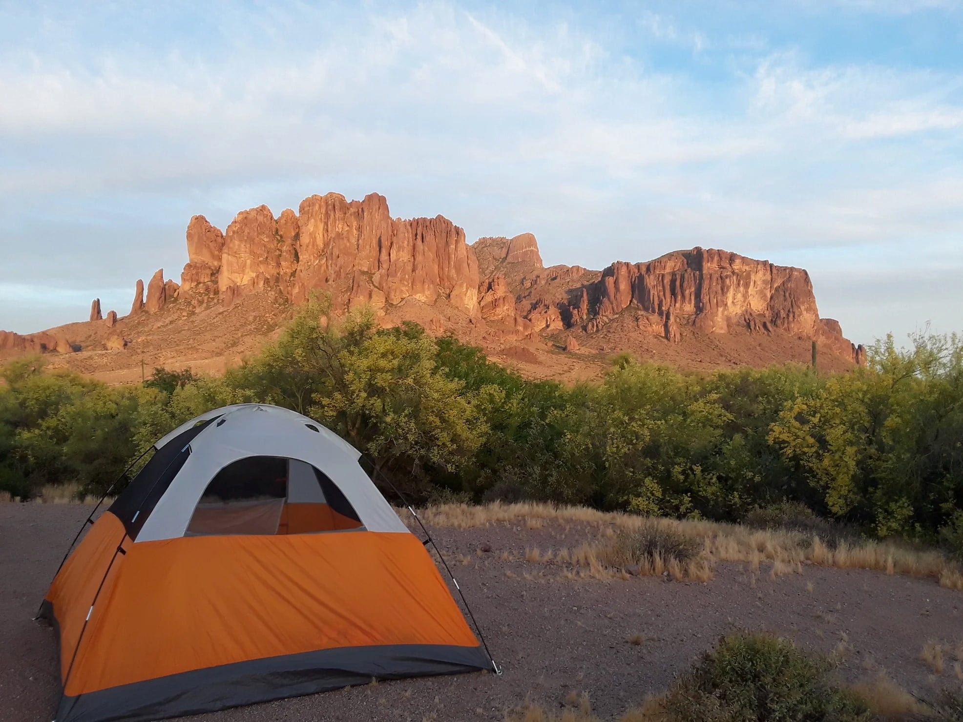 Orange tent with a wall of red rock in the background at Lost Dutchman State Park.
