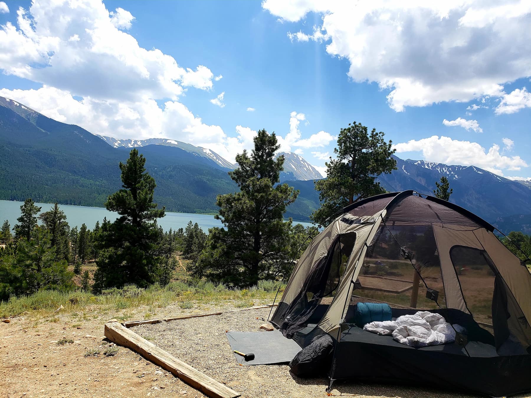 Tent on a platform beside the lake beneath a mountainous landscape.