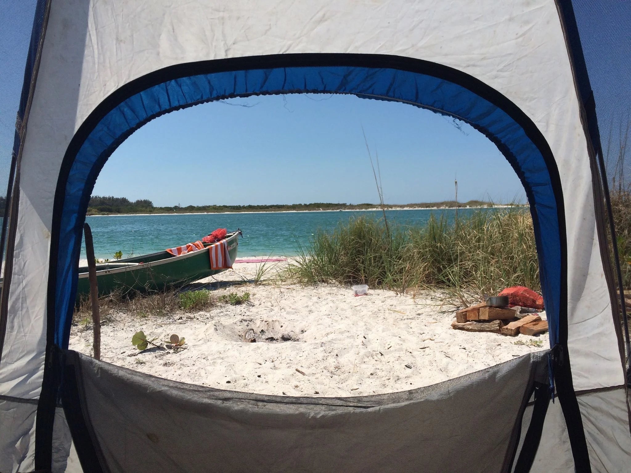 View of a white sand beach and ocean from inside a tent