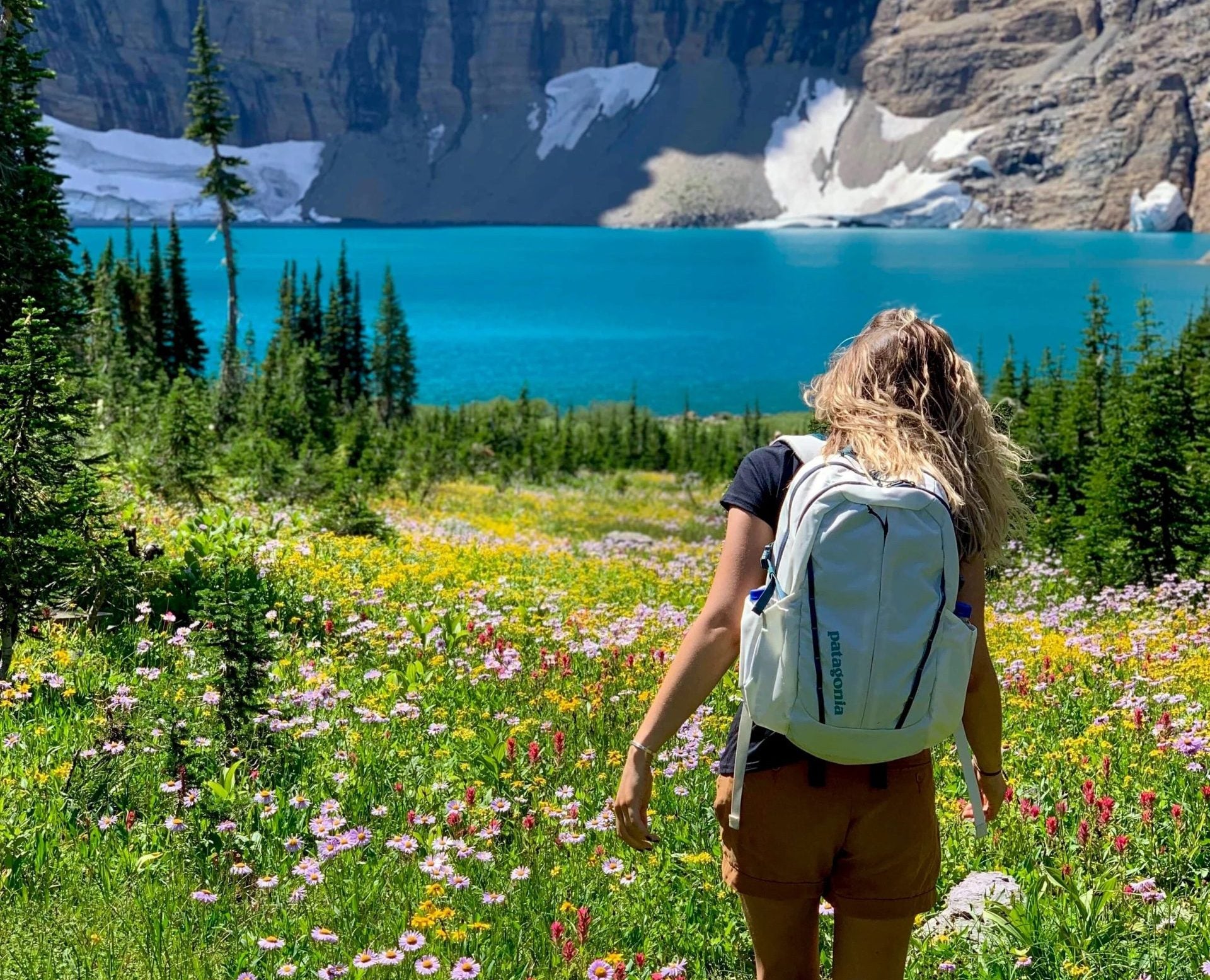 Woman walking through a field of wildflowers at Many Glacier Campground